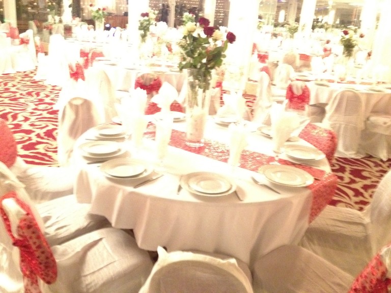 Tables rondes dressées en blanc et rouge avec bouquets de roses